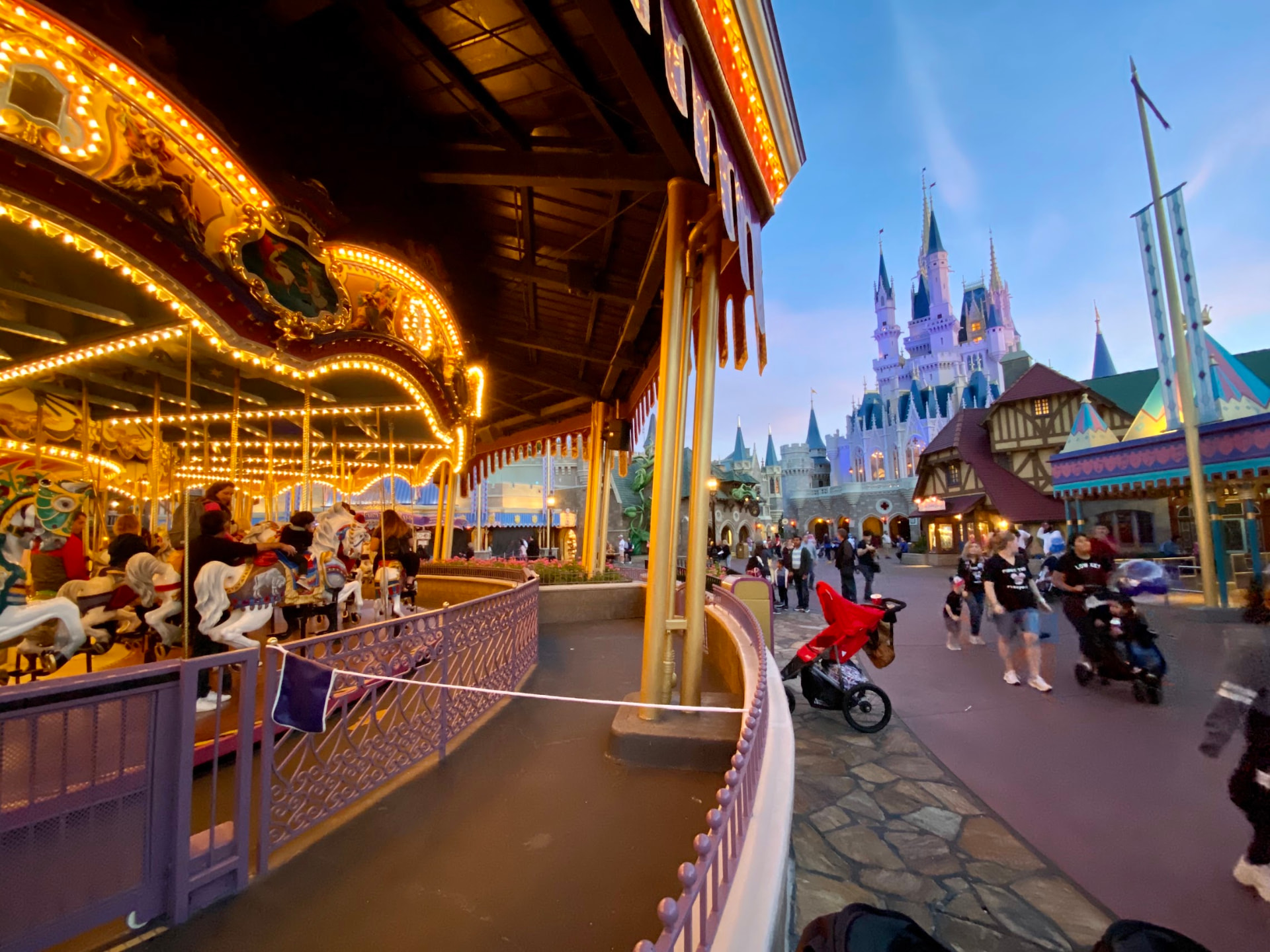 The Prince Charming Regal Carrousel glowing at dusk with Cinderella Castle in the background